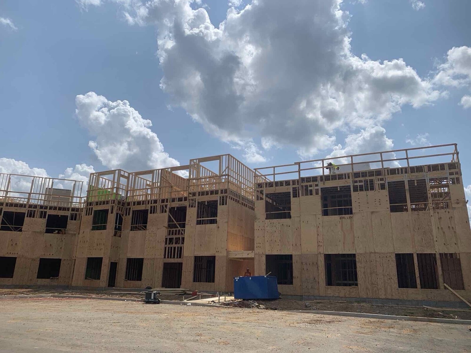 Framed multi-family building with aerial lift equipment staged on site
