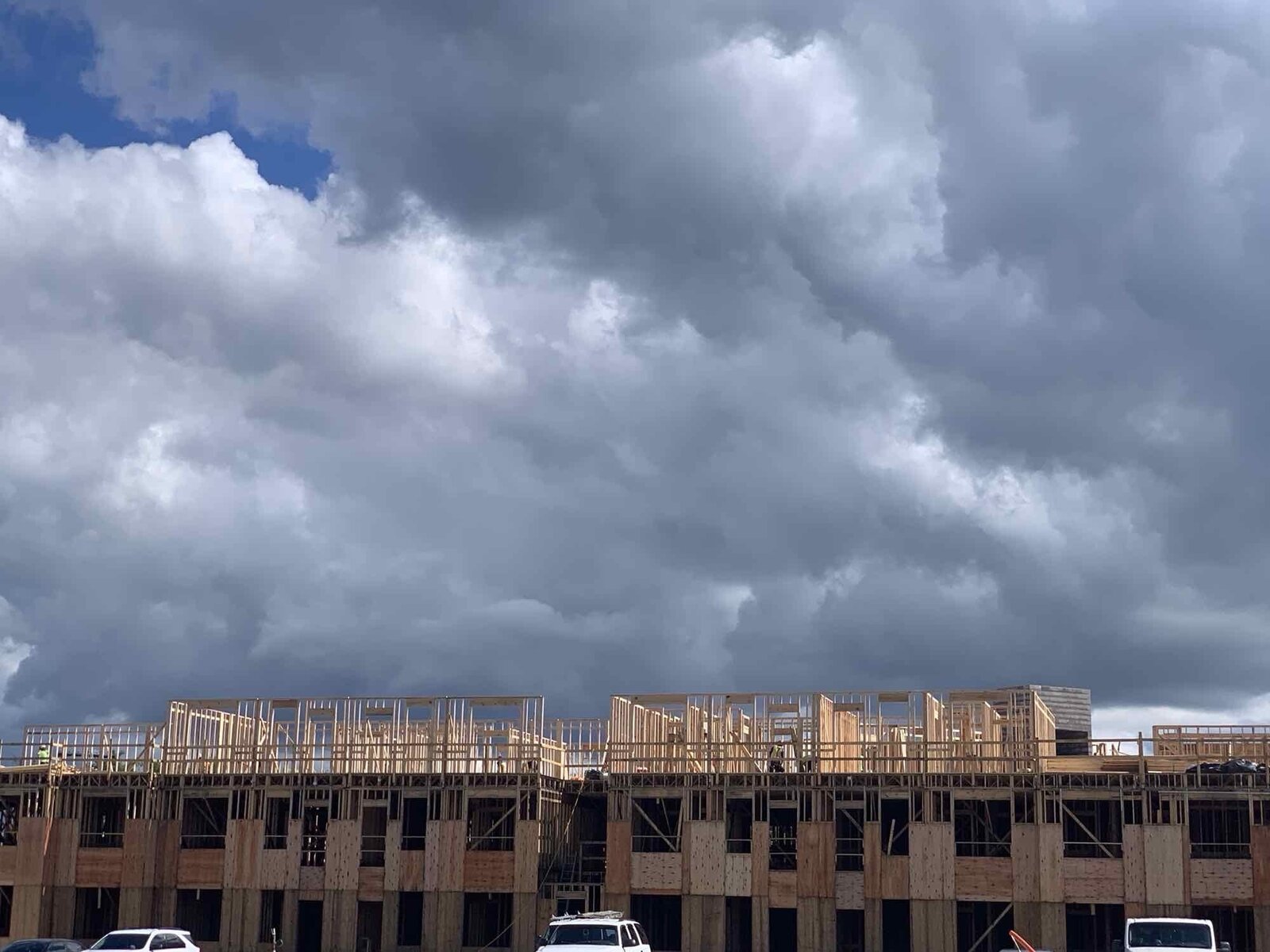 Row of framed multi-family buildings under a cloudy sky
