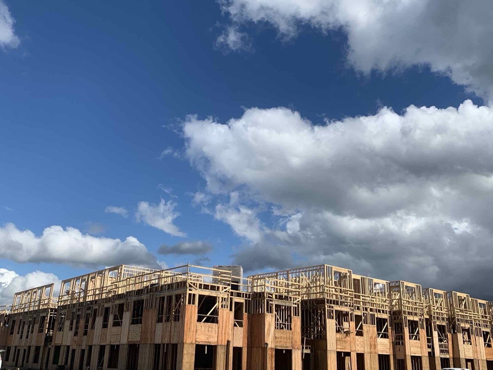 Row of framed multi-family buildings under a clear blue sky