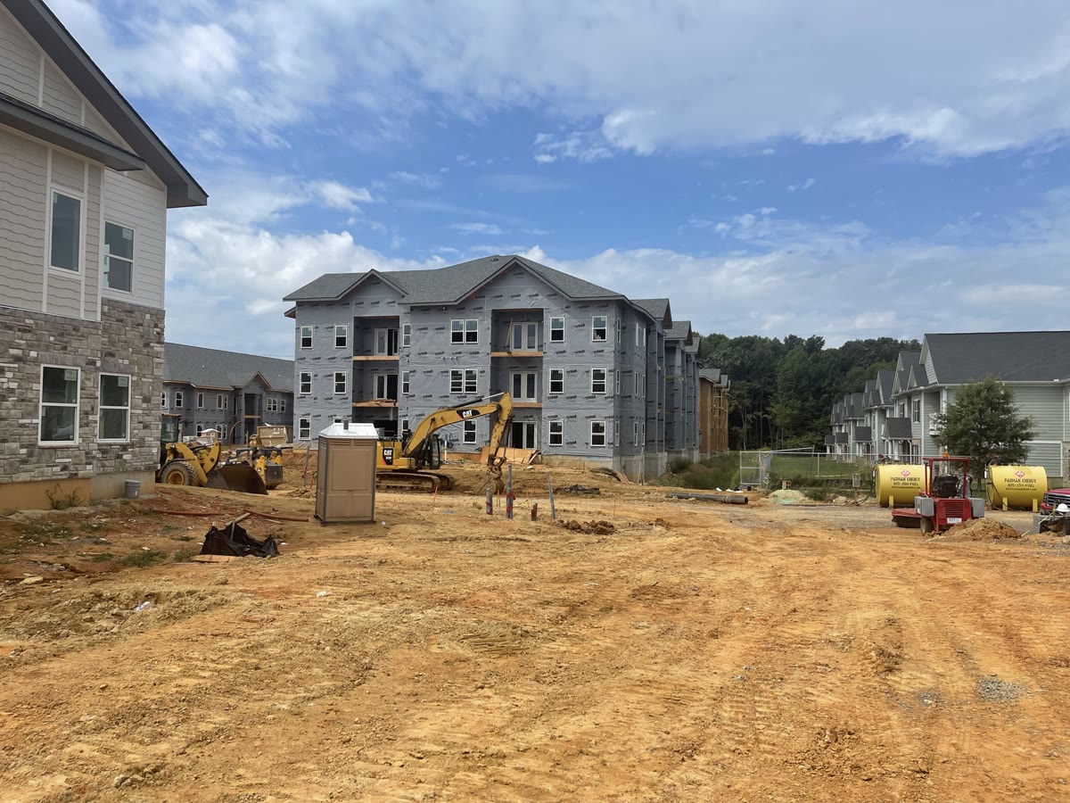 Active multi-family construction site with three-story framed buildings and heavy equipment