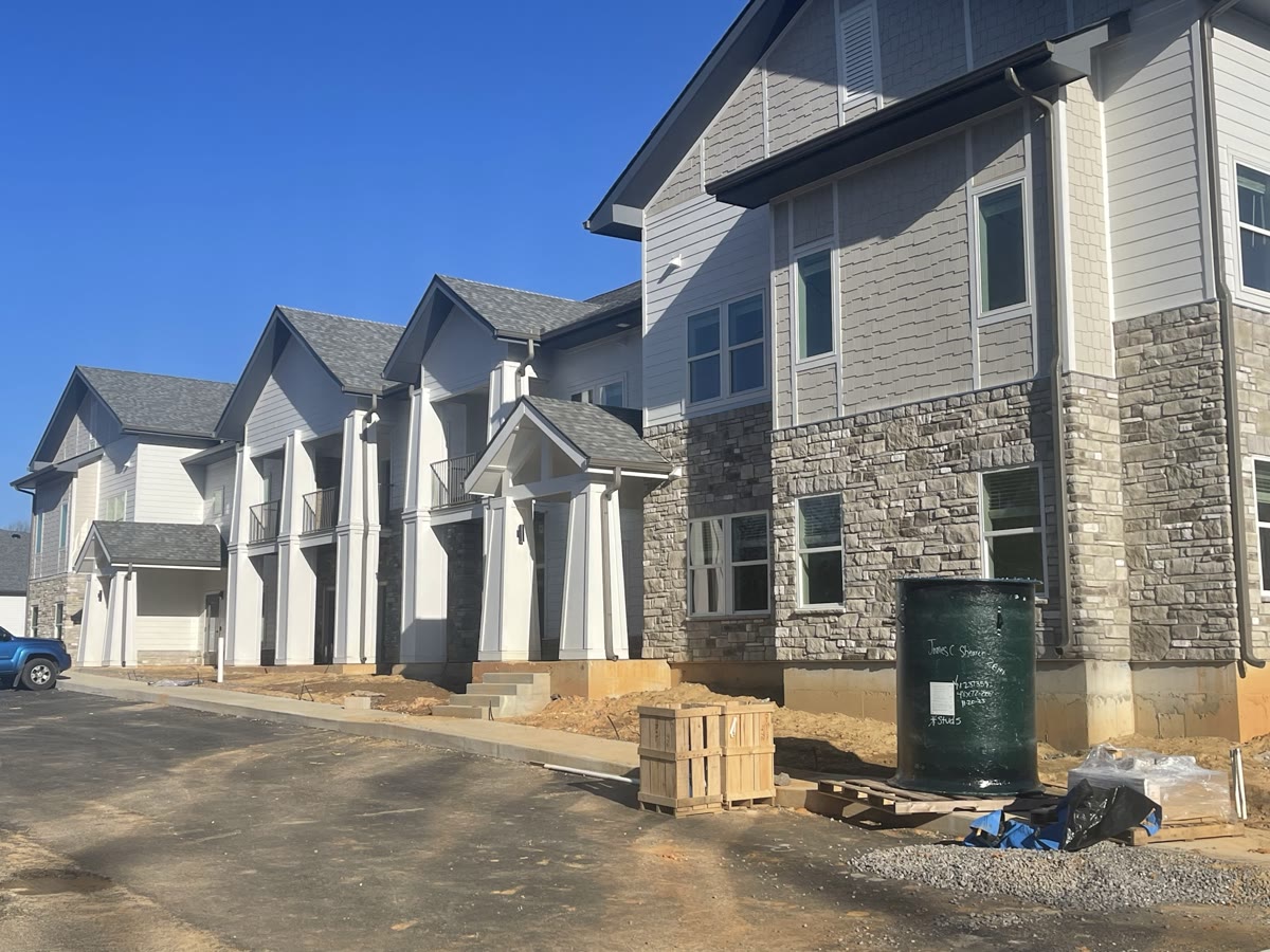 Row of completed multi-family townhomes with balconies and stone-clad base